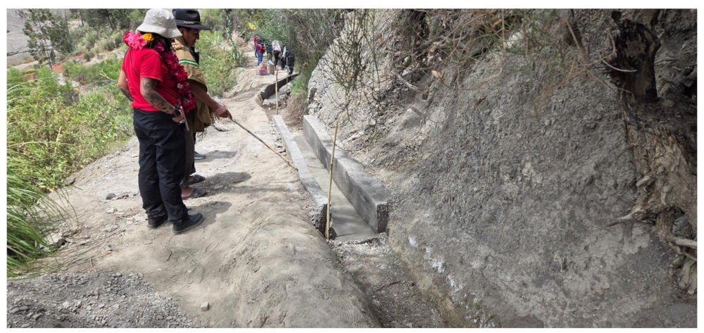 Dos personas observan un tramo de 5 metros de canalización cimentada. Se trata de un conducto mayoritariamente de tierra, en la Comunidad de Cahuayuma.