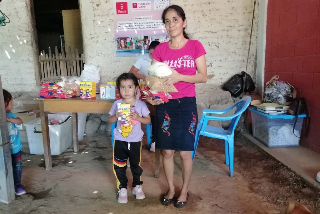 Una madre acompañada de su hija recoge insumos dentro del proyecto Gestión integral de la atención primaria en salud para las comunidades Chagüite centro y Lomas de San Antonio, Municipio de Tacuba, Ahuachapán (2024-2025)